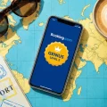 Smartphone affichant le niveau Genius 2 sur l'application Booking.com posé sur une carte du monde.