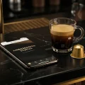 Application Nespresso affichant le statut Ambassadeur et un café espresso sur fond noir.