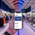 Application de fidélité La Team Intersport sur smartphone dans un magasin d'articles de sport.