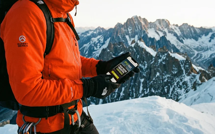 Randonneur en montagne consultant son application The North Face XPLR Pass pour un test de prototype.