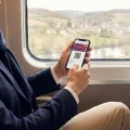 Une personne dans un train TGV utilisant sa carte Avantage SNCF dématérialisée sur son téléphone.