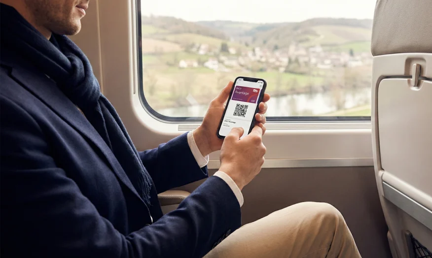 Une personne dans un train TGV utilisant sa carte Avantage SNCF dématérialisée sur son téléphone.