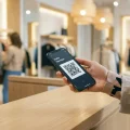 Une personne scannant son application H&M Hello Member à la caisse d'un magasin de mode moderne.