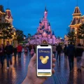 Main Street USA à Disneyland Paris au crépuscule avec un smartphone affichant le Disneyland Pass Gold.