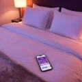 Smartphone sur un lit d'hôtel affichant l'application Hotels.com avec 9 vignettes sur 10.