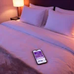 Smartphone sur un lit d'hôtel affichant l'application Hotels.com avec 9 vignettes sur 10.