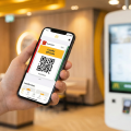 Un smartphone affichant le QR code de fidélité McDo+ devant une borne de commande McDonald's