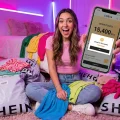 Influenceuse montrant son solde de points Shein sur smartphone avec plein de vêtements.
