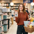 Cliente heureuse utilisant l'application de fidélité La Foir'Fouille en magasin pour acheter de la décoration.