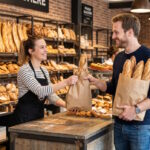 Client souriant profitant de l'offre 4 baguettes pour le prix de 3 dans une boulangerie Marie Blachère.