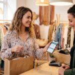 Cliente utilisant son compte fidélité Promod Club sur son smartphone en boutique.