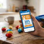 Smartphone affichant l'application E.Leclerc et la cagnotte Tickets E.Leclerc avec des chocolats de Pâques.