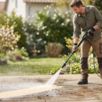 Homme nettoyant sa terrasse en bois avec le nettoyeur haute pression Parkside vert et noir.