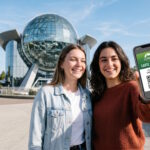 Visiteurs utilisant leur Carte Saison numérique sur smartphone devant le pavillon du Futuroscope.