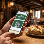 Un client utilisant sa carte de fidélité numérique La Pataterie sur son smartphone dans un restaurant à l'ambiance rustique.
